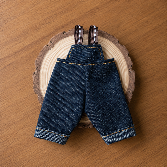 Toy denim overalls with suspenders on a wooden surface