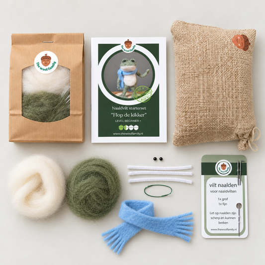 A flat-lay view of a felt knitting starter kit on a light gray background. The kit contains a brown paper bag of white and green wool, a green and white instruction card, a burlap pouch, two balls of wool (one white, one green), two white pipe cleaners, a blue felted scarf, two small black beads, and a green elastic band.